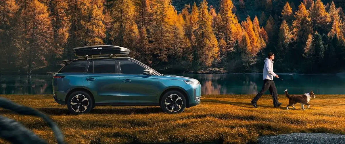 Sonbahar manzarasında göl kenarında sergilenen tavan bagajlı mavi JAECOO SUV modeli
