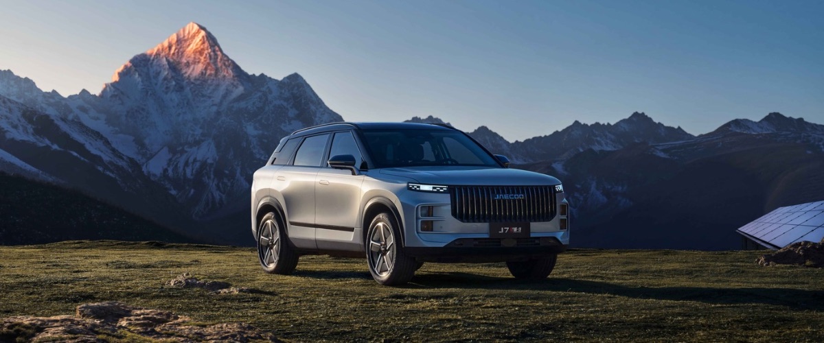 Karlı dağların önündeki çimenlik arazide duran açık gümüş renkli JAECOO 7 SUV modeli.