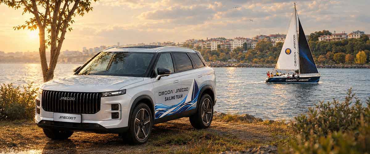 Ön planda OMODA | JAECOO Sailing Team yazılı bir SUV araç ve arka planda denizde seyreden markalı yelkenli.