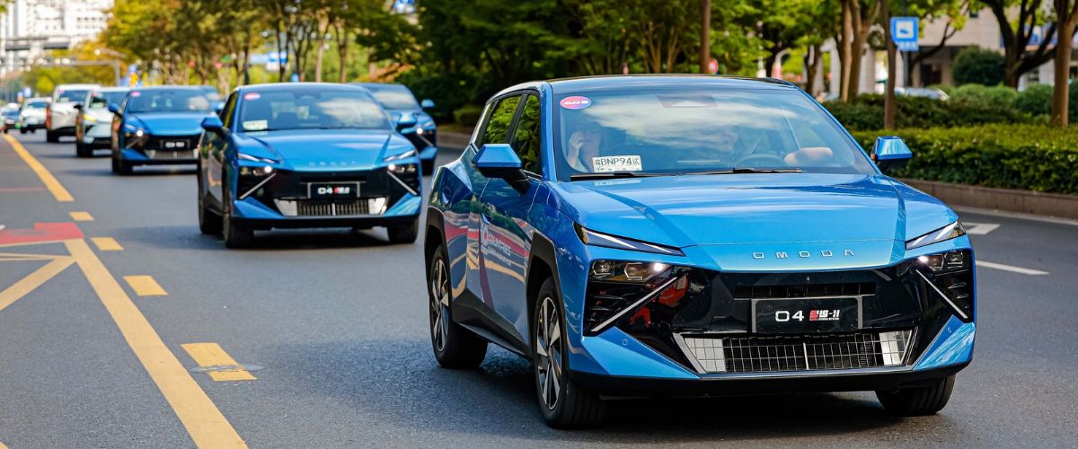 Super Hybrid Marathon etkinliği kapsamında ağaçlıklı bir şehir içi yolda konvoy halinde ilerleyen mavi renkli OMODA 4 SHS-H süper hibrit modelleri